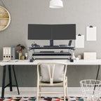 Modern office setup with a standing desk, computer monitors, and office supplies.