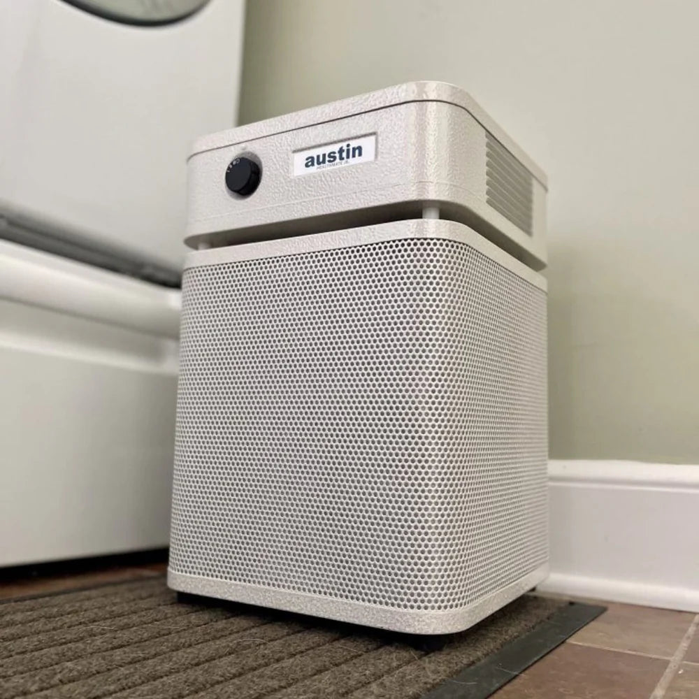 White air purifier with 'austin' branding on a carpeted floor.