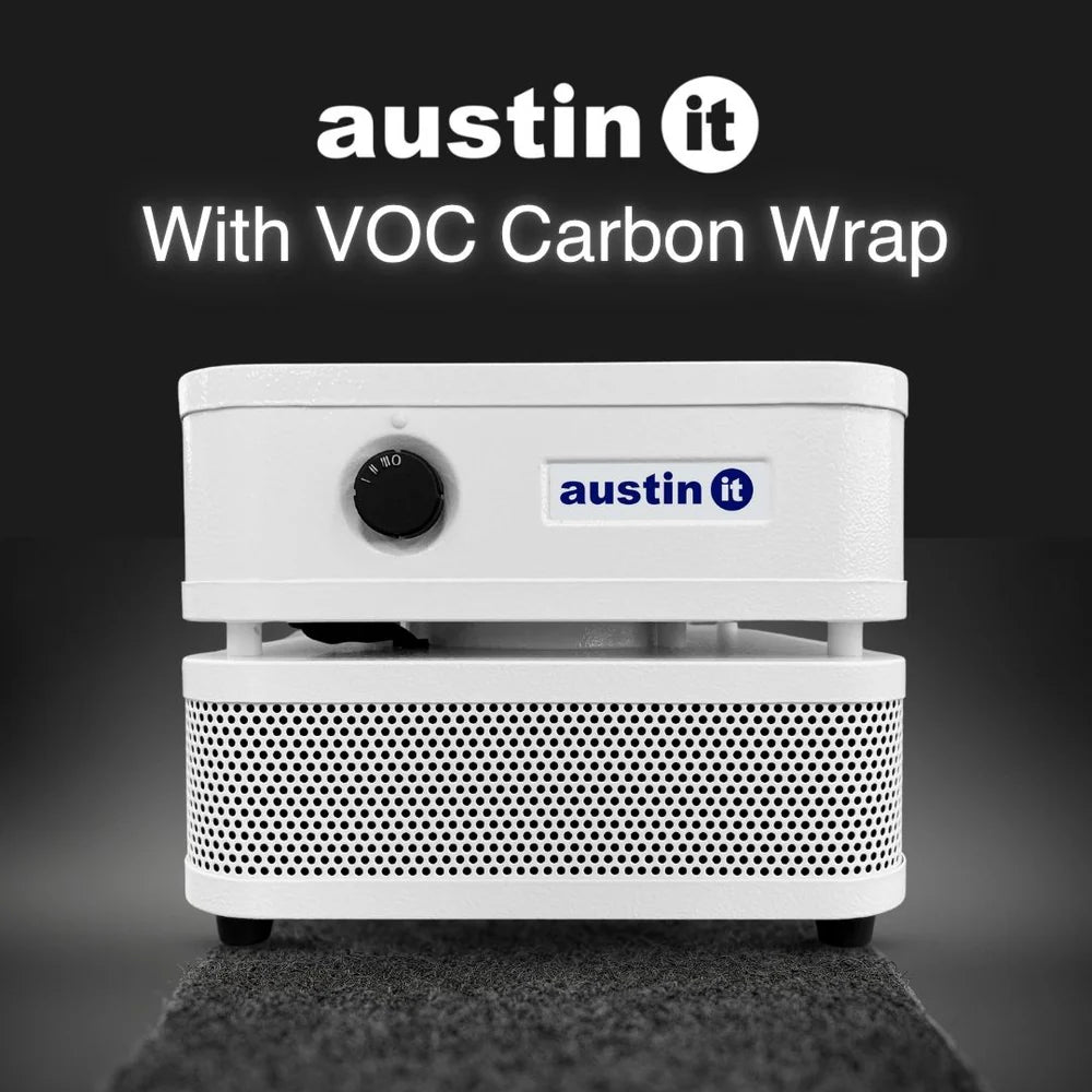 A white Austin It portable projector with a perforated front grille, shown against a dark gray gradient background with the text 'austin it With VOC Carbon Wrap' at the top.