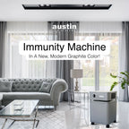 Modern living room with a gray sofa and air purifier, featuring 'austin air systems' branding.