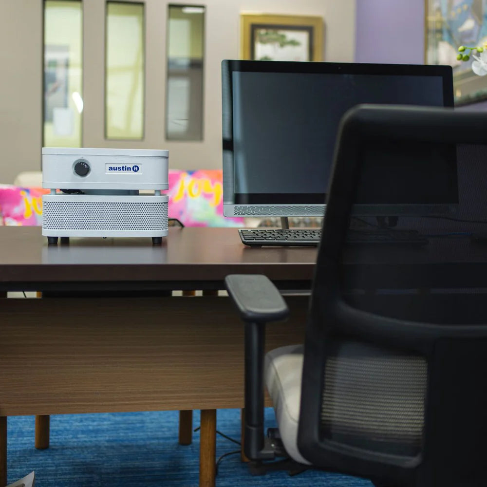 Office desk with computer setup, chair, and colorful decorations in the background