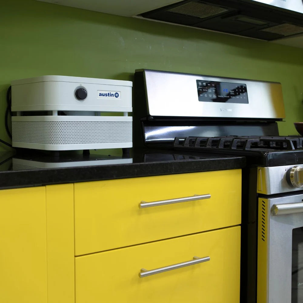 Kitchen with yellow cabinets, black countertop, and stainless steel appliances including a coffee machine and oven.