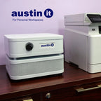 White electronic device with 'austin it' branding on a wooden surface against a light purple wall.
