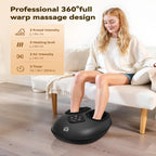 A woman sits on a cream sofa in a bright living room while using a black foot massage machine placed on the floor. The product has a digital control panel and is shown with promotional text highlighting its 360-degree full warp massage design and adjustable knhead intensity, heating level, air intensity, and timer.