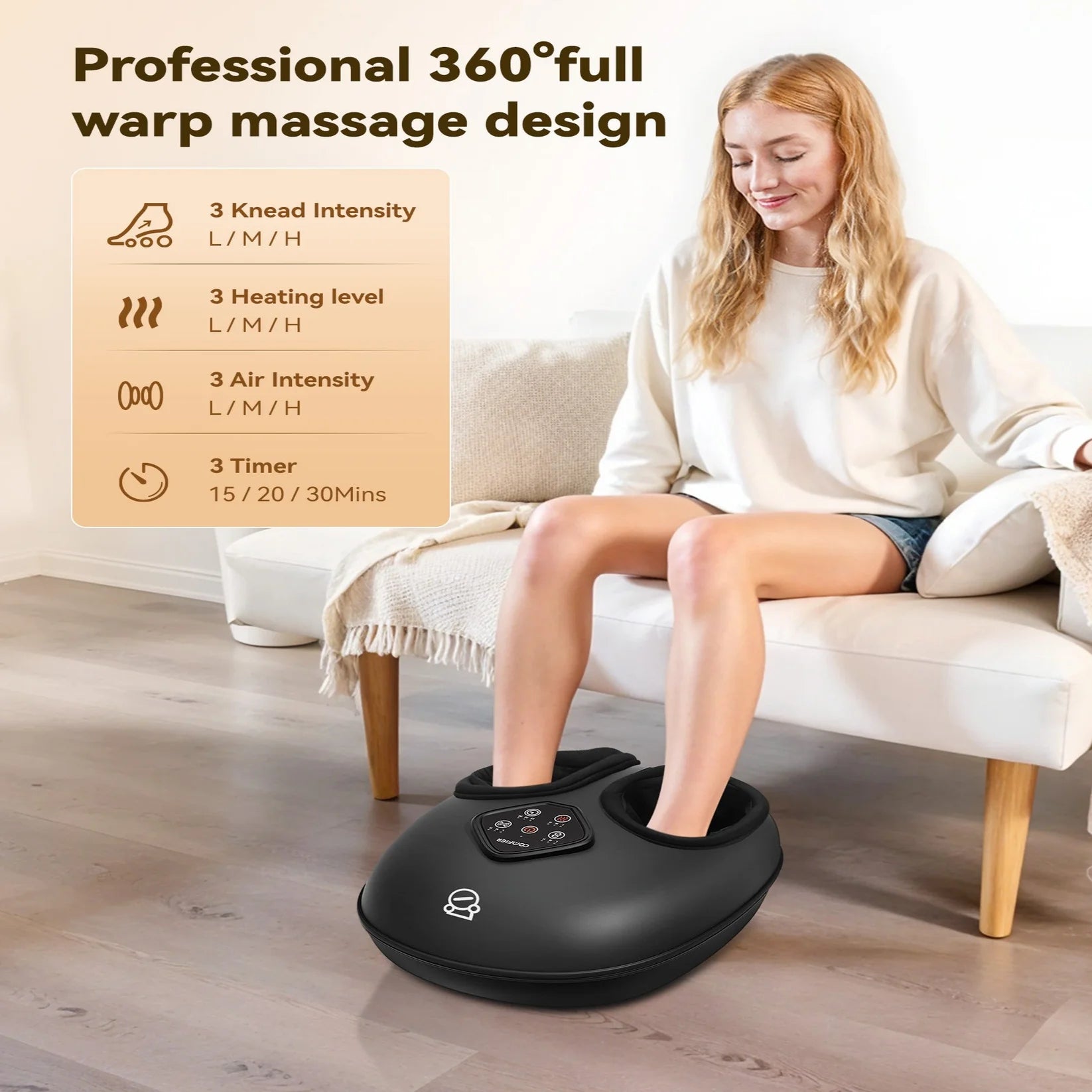 A woman sits on a cream sofa in a bright living room while using a black foot massage machine placed on the floor. The product has a digital control panel and is shown with promotional text highlighting its 360-degree full warp massage design and adjustable knhead intensity, heating level, air intensity, and timer.