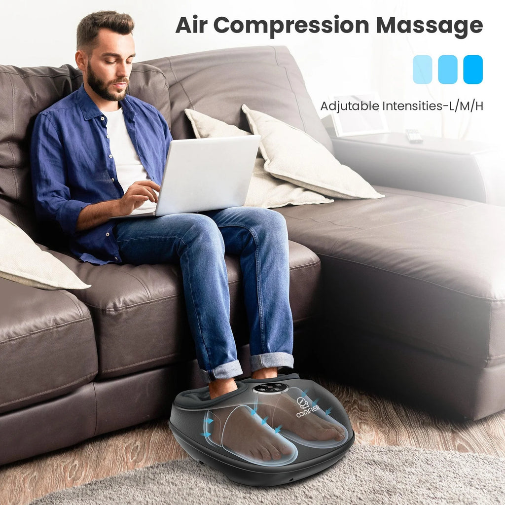 A man sitting on a brown leather sofa using an air compression massage foot massager on the floor while working on a laptop. The image includes text overlays reading 'Air Compression Massage' and 'Adjustable Intensities-1/M/H' with three blue intensity indicators.